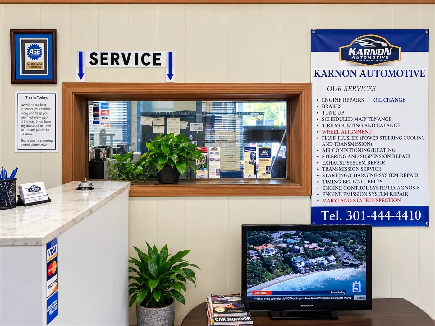 The front counter at Karnon Automotive: the service window, an ASE Master Technician plaque and the board of services