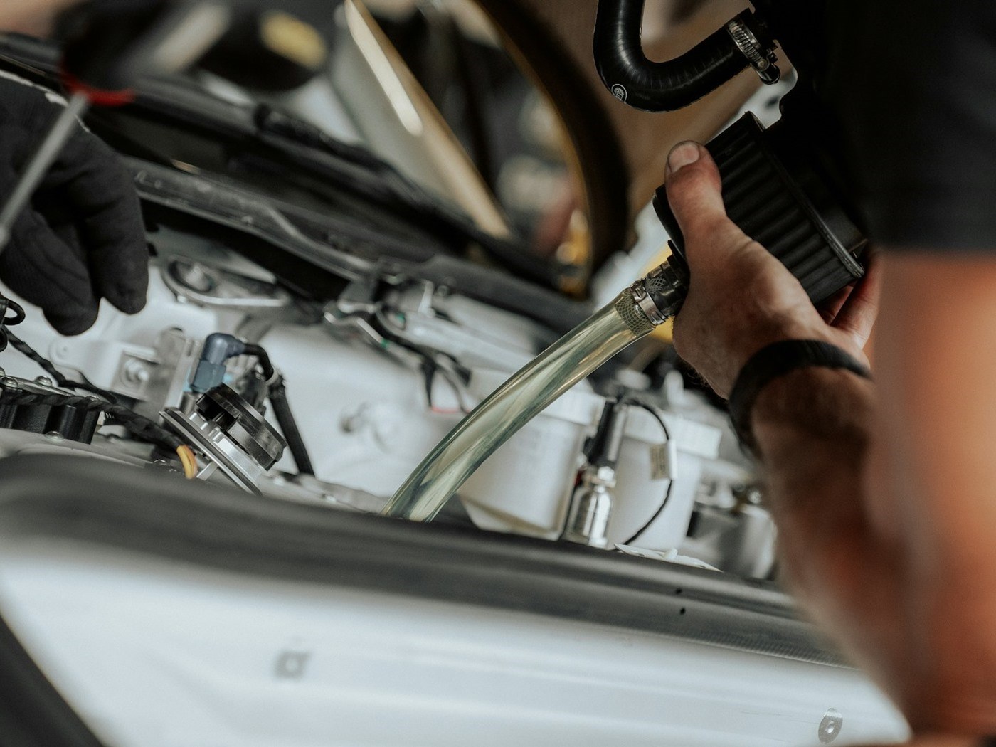 A technician inspecting an engine bay with the hood raised