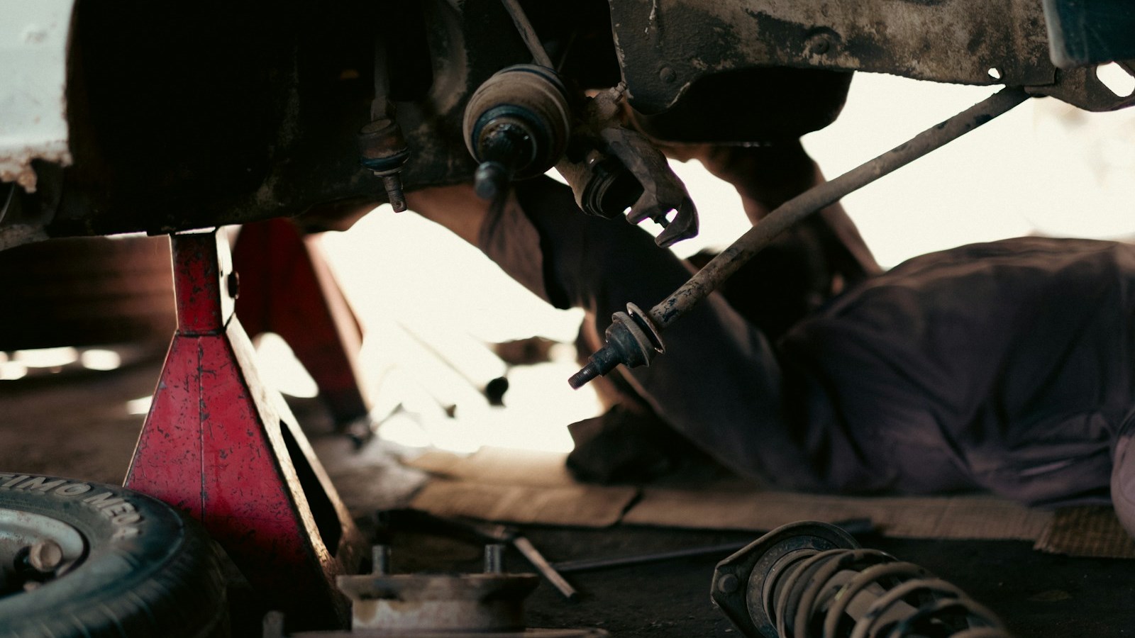 A technician working underneath a car on the suspension and steering parts