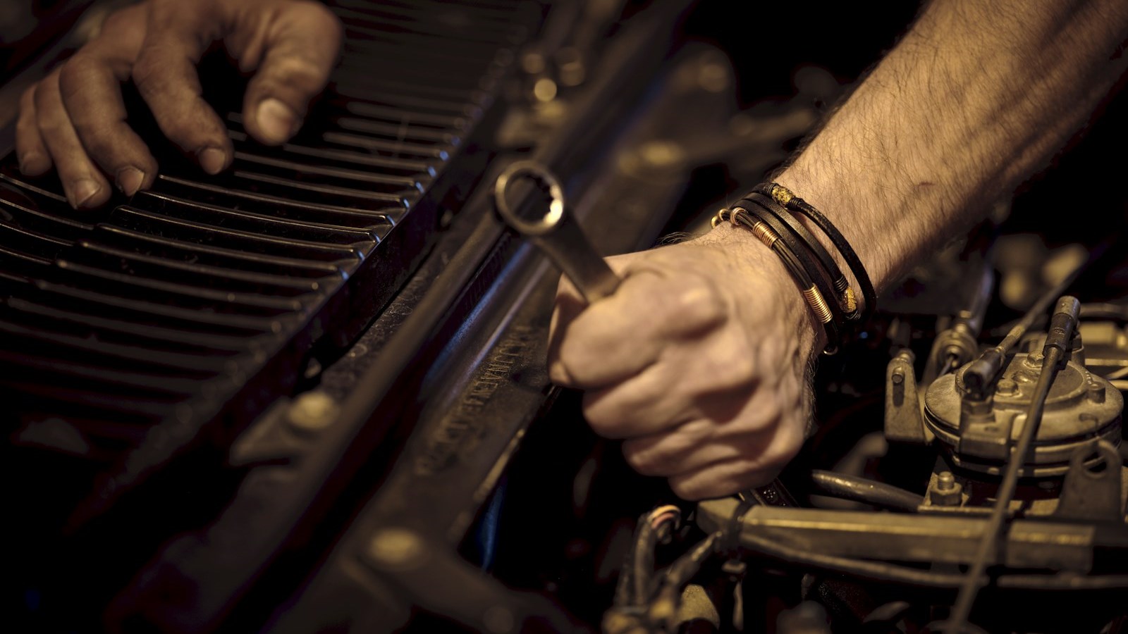 Hands working on an engine with a wrench