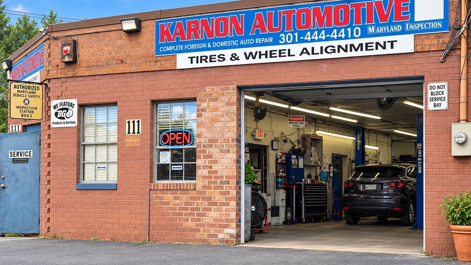 The front of Karnon Automotive on N Stonestreet Avenue: brick storefront, the sign with the phone number, and an open service bay