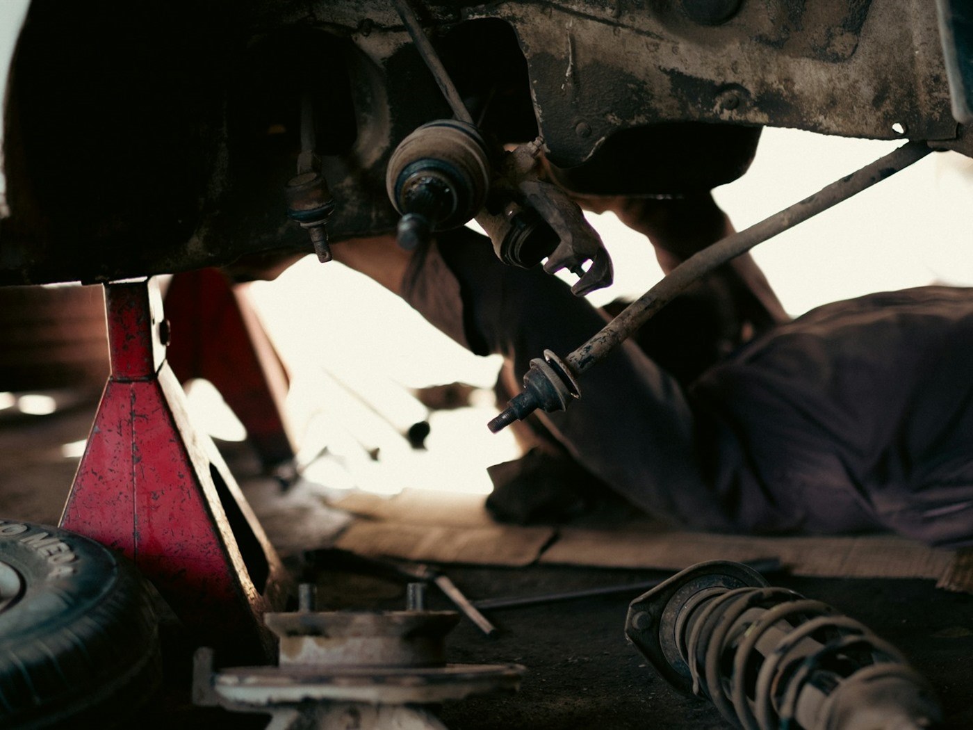 A technician working on the wheel and suspension of a car on a lift
