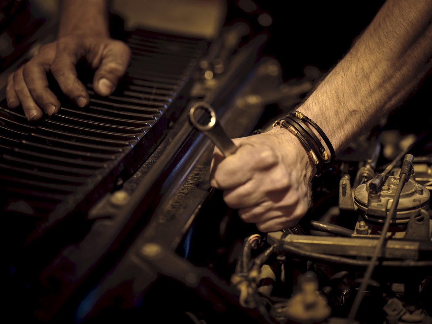 A technician's hands working on an engine with a wrench